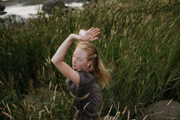 A young woman dances with grace surrounded by lush greenery, embodying peace and harmony with nature.