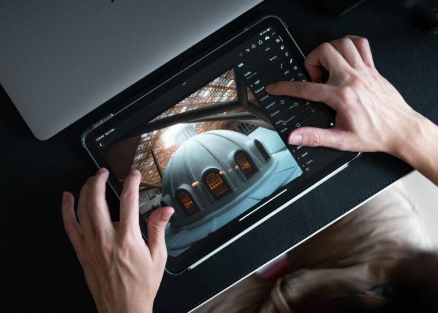 Hands editing architectural photo on tablet using Lightroom app