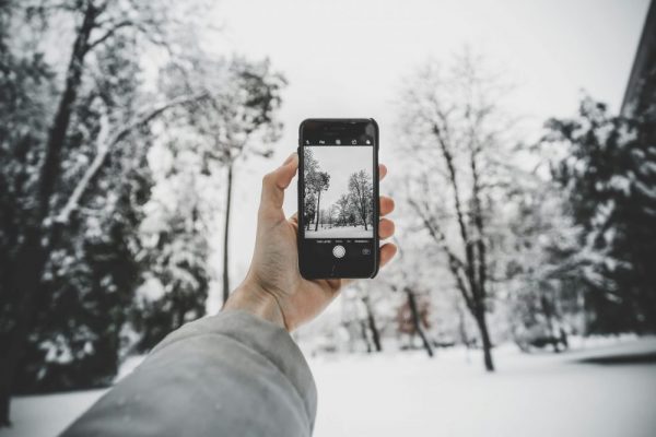 手持手機拍攝雪景的場景，象徵在拍照或切換功能時可能遇到卡住