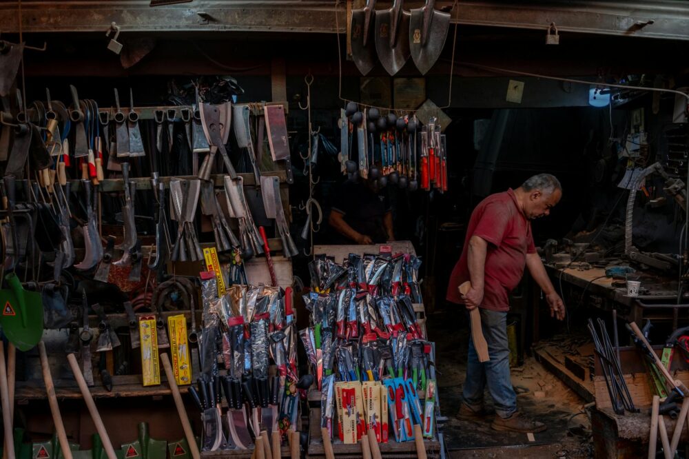 An elderly blacksmith working in his tool-filled workshop in İzmir, Türkiye.