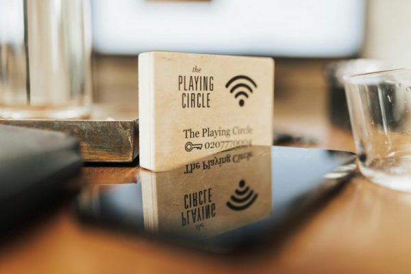 手機熱點變慢原因與解決:頻段選擇及流量限制指南 A wooden block displaying Wi-Fi details sits on a modern office desk.