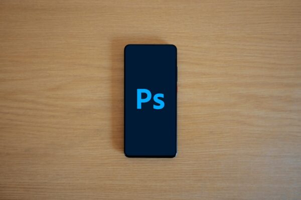 Top view of a smartphone showing Adobe Photoshop on a wooden surface.