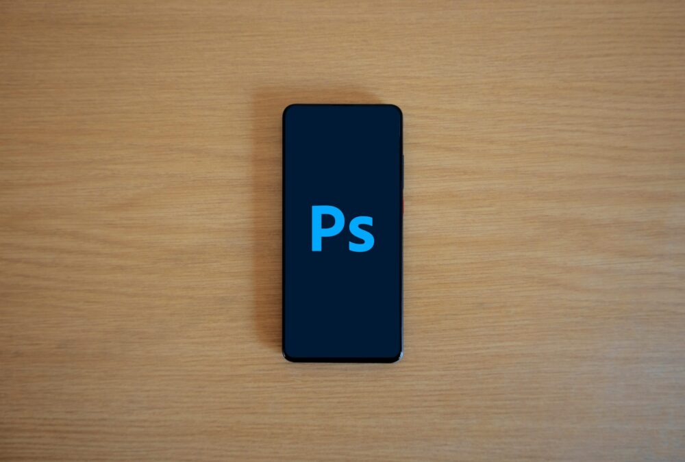 Top view of a smartphone showing Adobe Photoshop on a wooden surface.