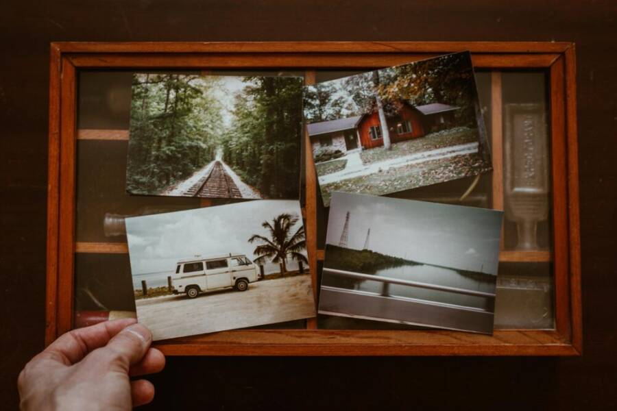 A collection of nostalgic vintage photographs in a wooden box, evoking travel memories.