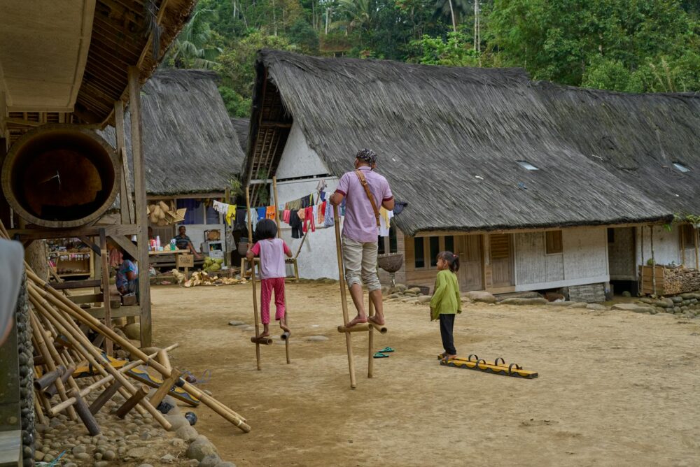 A vibrant depiction of a rural village with children practicing stilt walking.