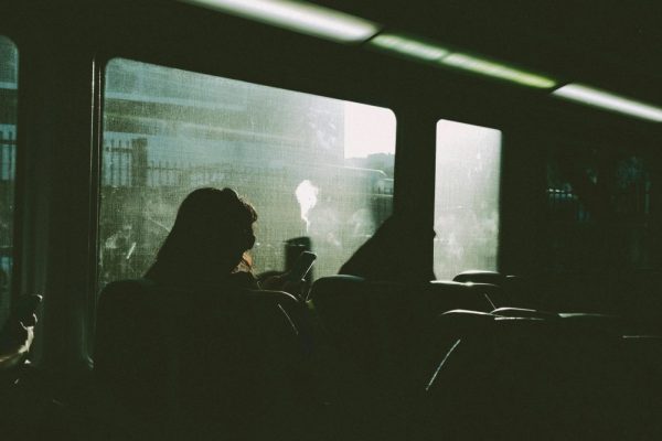 旅遊前資料備份清單:防範手機遺失風險 Silhouette of a person using a phone on a train journey, sunlight streaming in.
