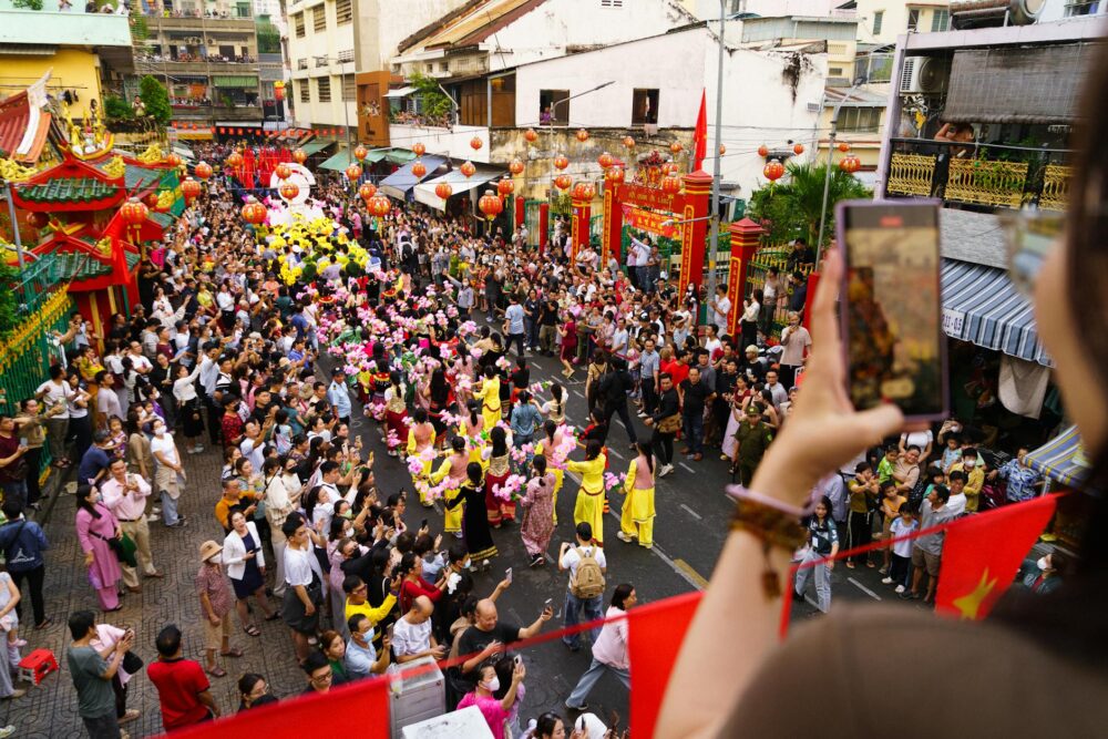 Colorful Tet festival parade in Ho Chi Minh City with street performers and a lively crowd.