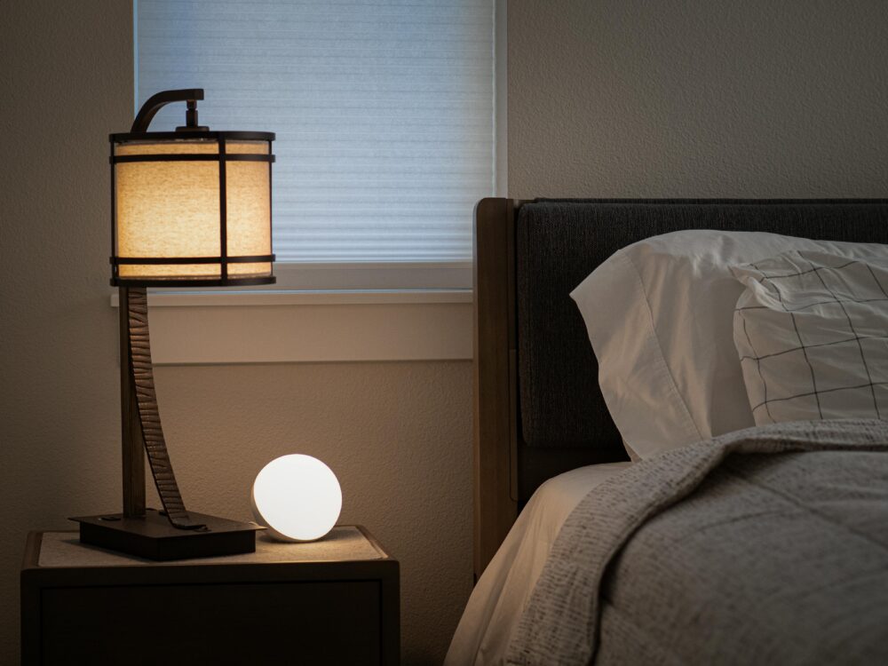 Serene and inviting bedroom interior featuring a warm-lit lamp and cushioned bed.