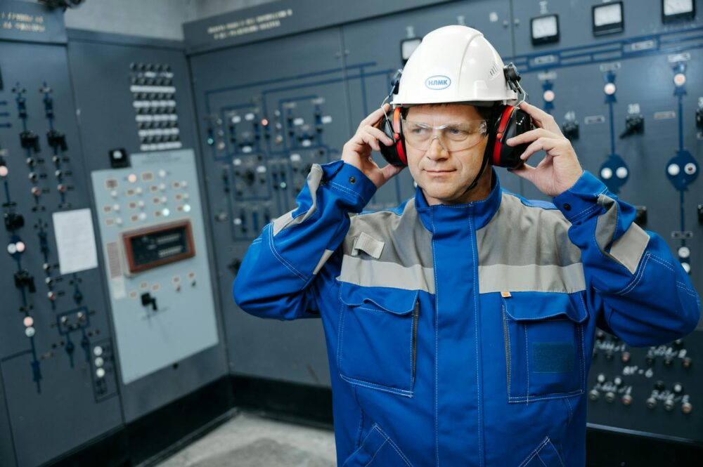 Engineer wearing protective gear in a control room, emphasizing safety and technology.