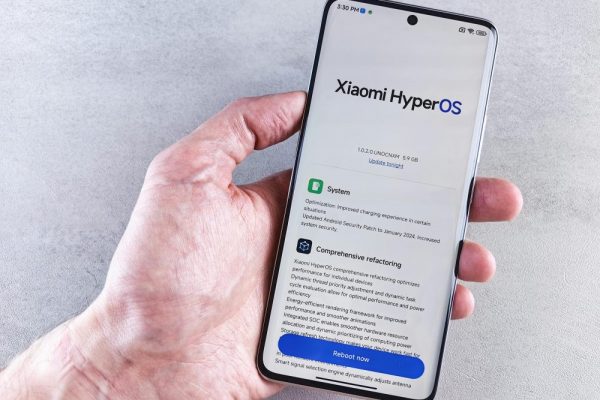 手機系統降級可行嗎?風險評估與資料備份全指南(iOS 與 Android) Close-up of a hand holding a Xiaomi smartphone with HyperOS interface, showcasing comprehensive refactoring and system update details.
