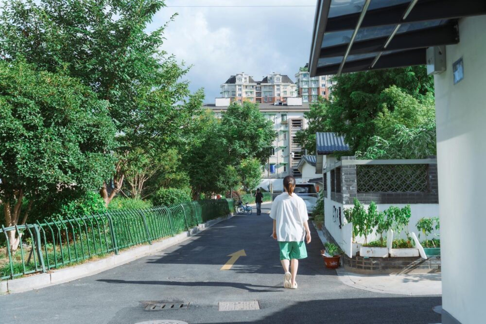 Young woman walking down a leafy street under bright夏日陽光漫步的年輕女性