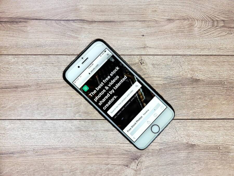 Top view contemporary mobile phone with opened website on screen placed on wooden table
