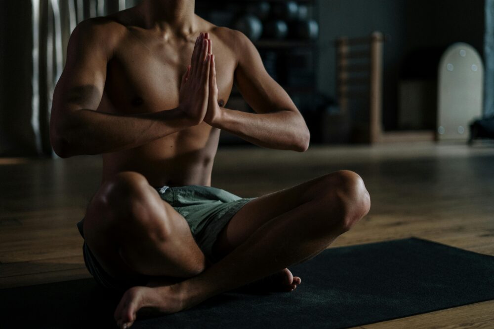A young man meditates in a yoga studio, promoting relaxation and wellness.