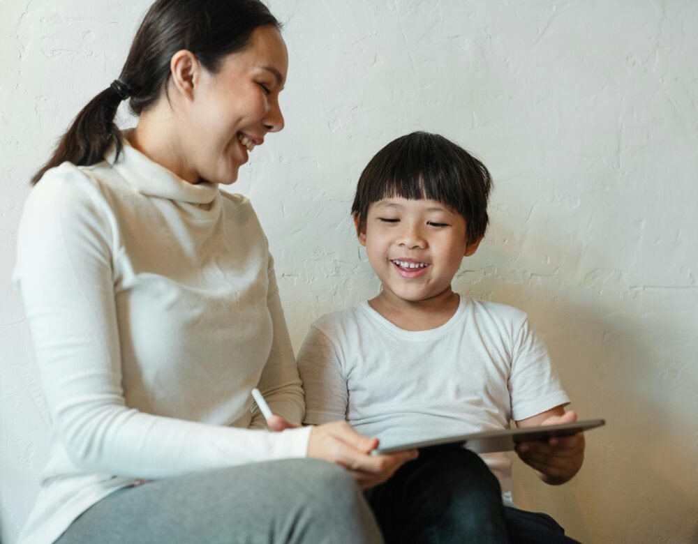 A happy mother and child enjoying quality time together with a tablet indoors.