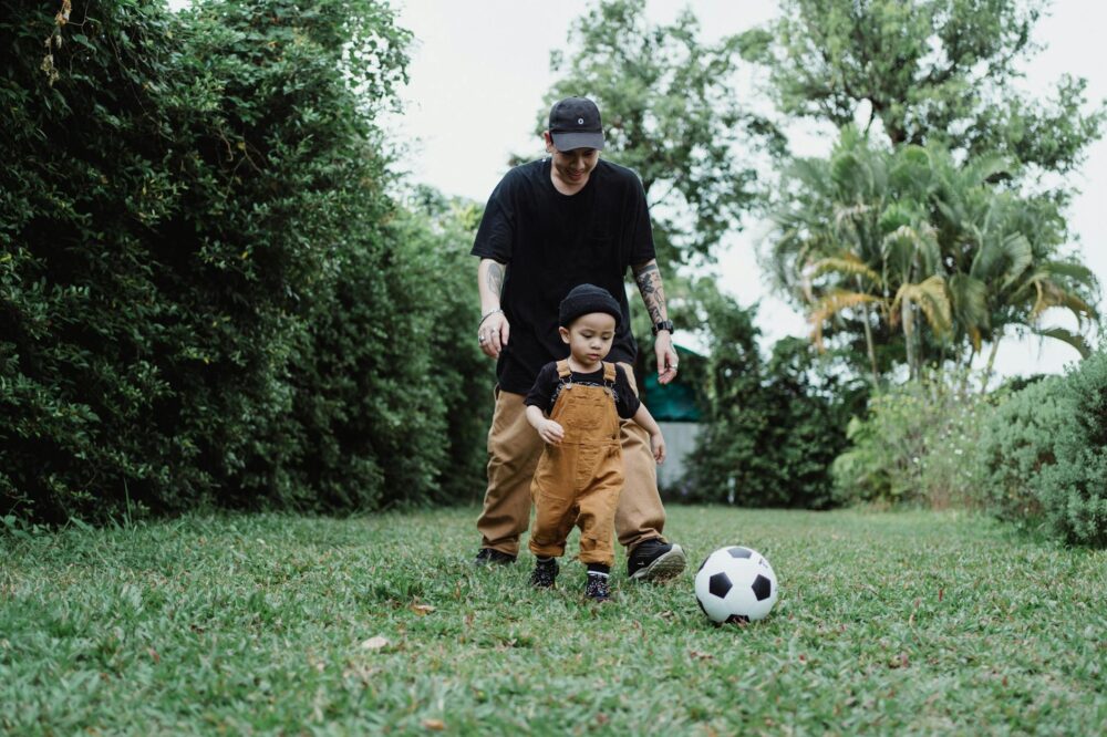 A father and son enjoying a playful game of soccer together in the backyard.