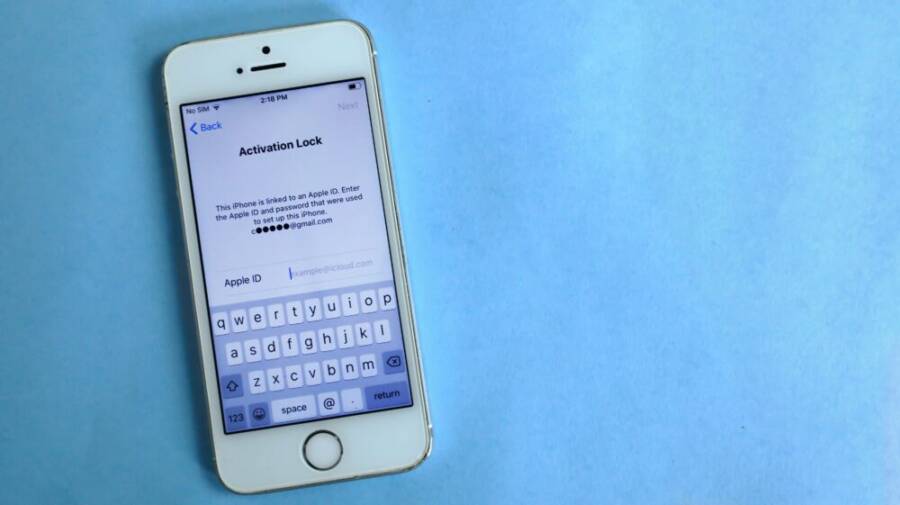 Top view of a smartphone showing activation lock screen on light blue surface.