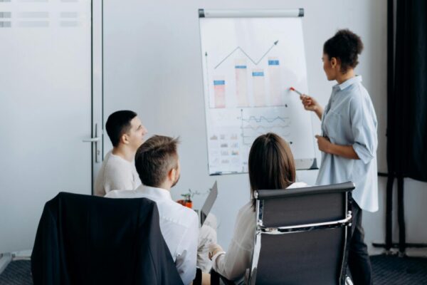 Business team in meeting with presenter discussing charts on a flip board.