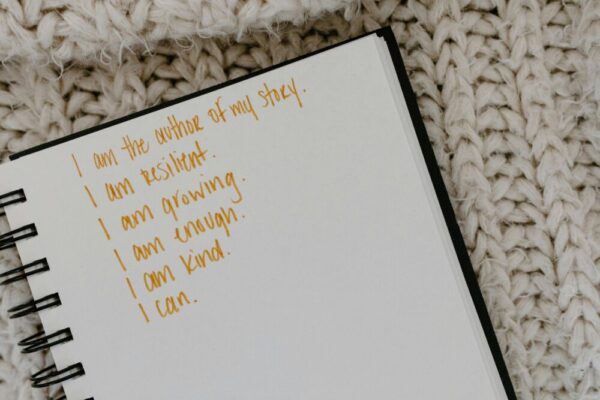 Notebook with handwritten affirmations on knitted fabric background
