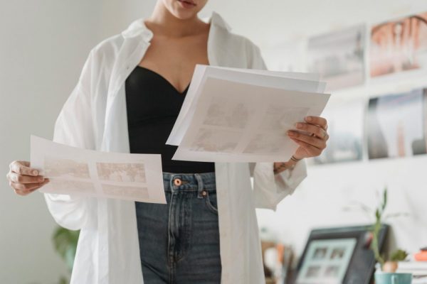 照片去重工具評測:免費 vs 付費哪個更值得 Woman in casual attire analyzing printed photos indoors with focus on creative work.