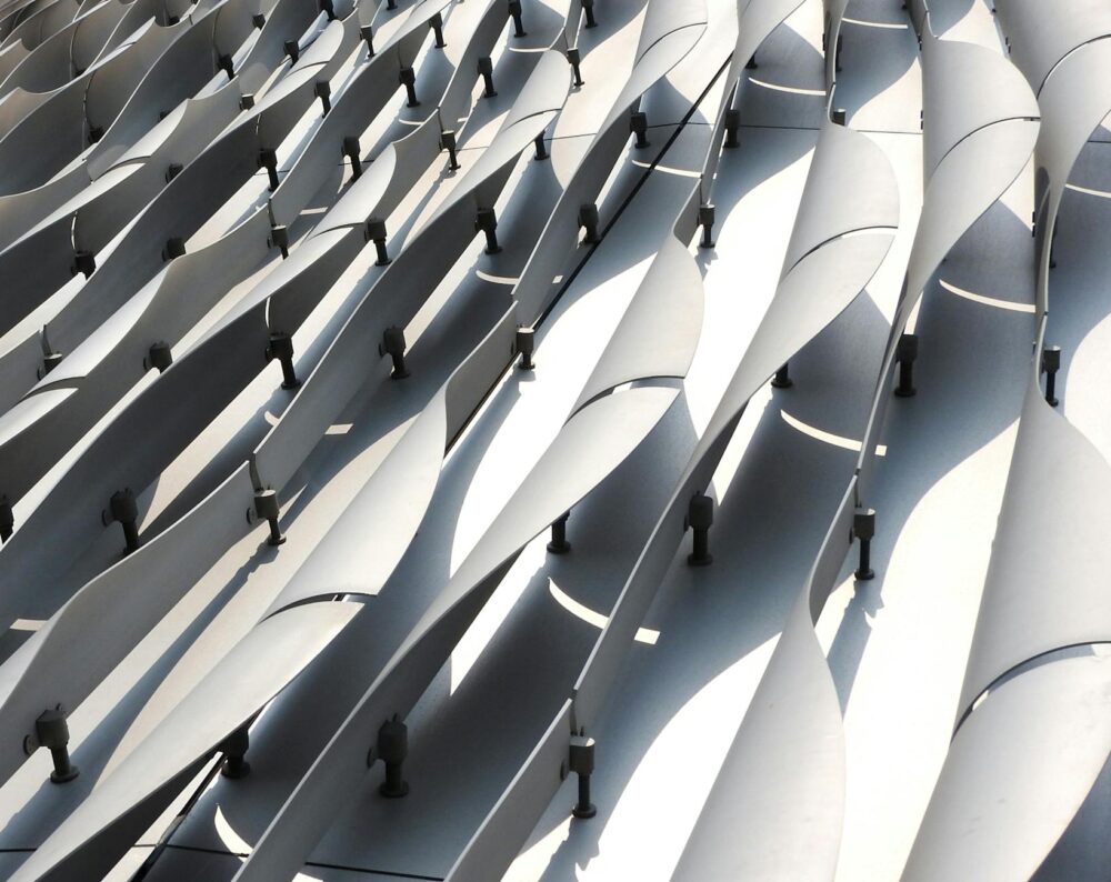 Abstract view of a contemporary architectural facade with curved metal elements in bright sunlight.