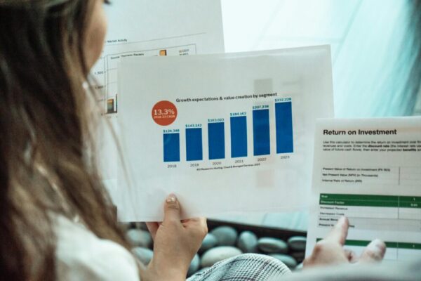 Person analyzing financial graphs and ROI reports, focusing on investment growth.