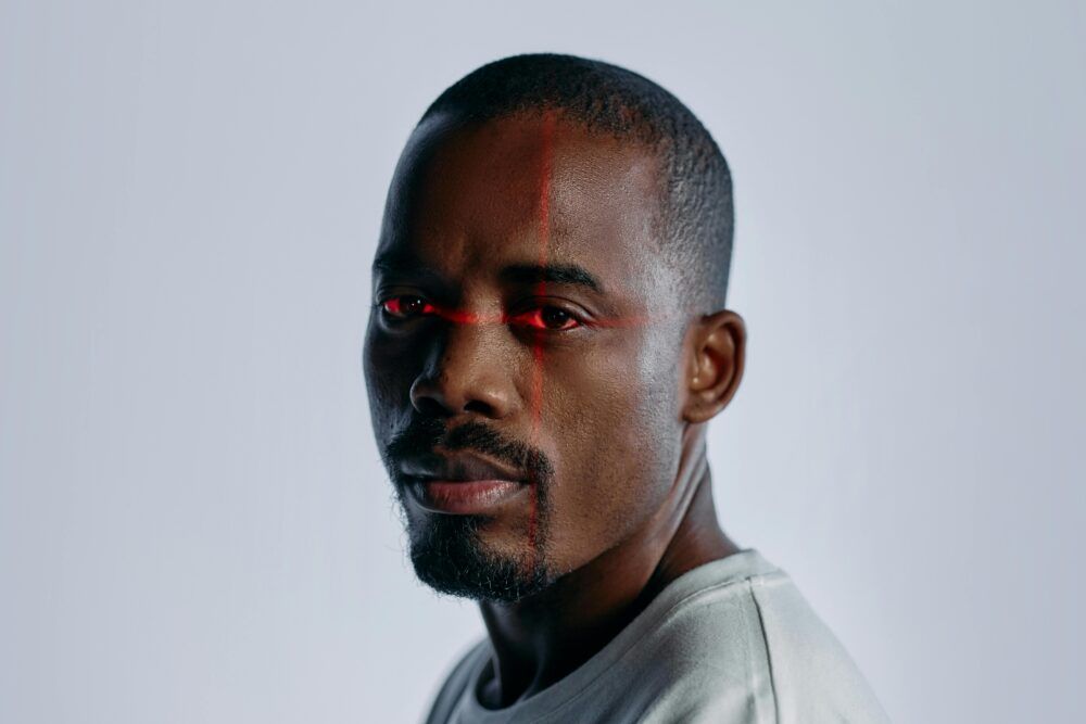 Close-up of a man with a futuristic laser scanning effect over his eyes, suggesting technology and identity themes.