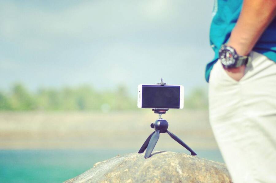 A smartphone set up on a tripod near a serene lake under daylight in Sri Lanka.