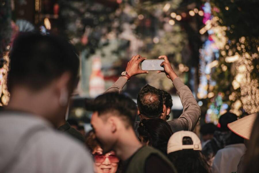 A lively street festival in Hanoi, Vietnam with people capturing moments on smartphones