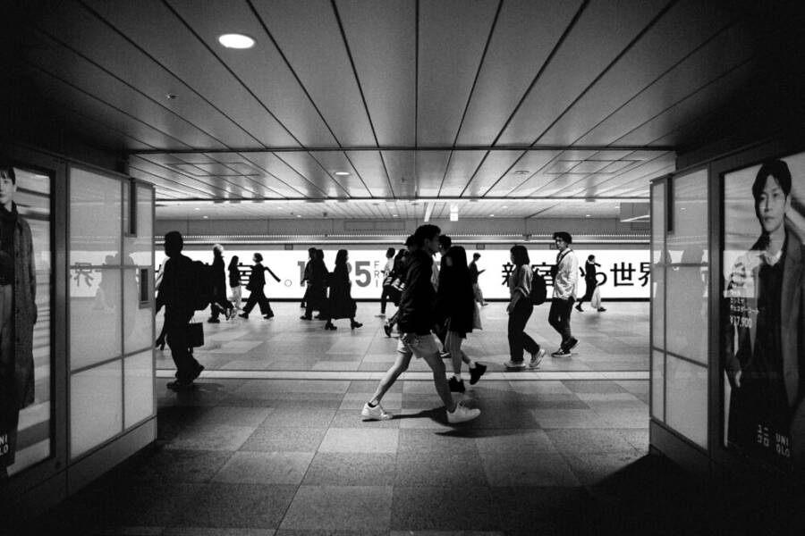 Black and white photo capturing a bustling Tokyo subway station with silhouetted people walking.