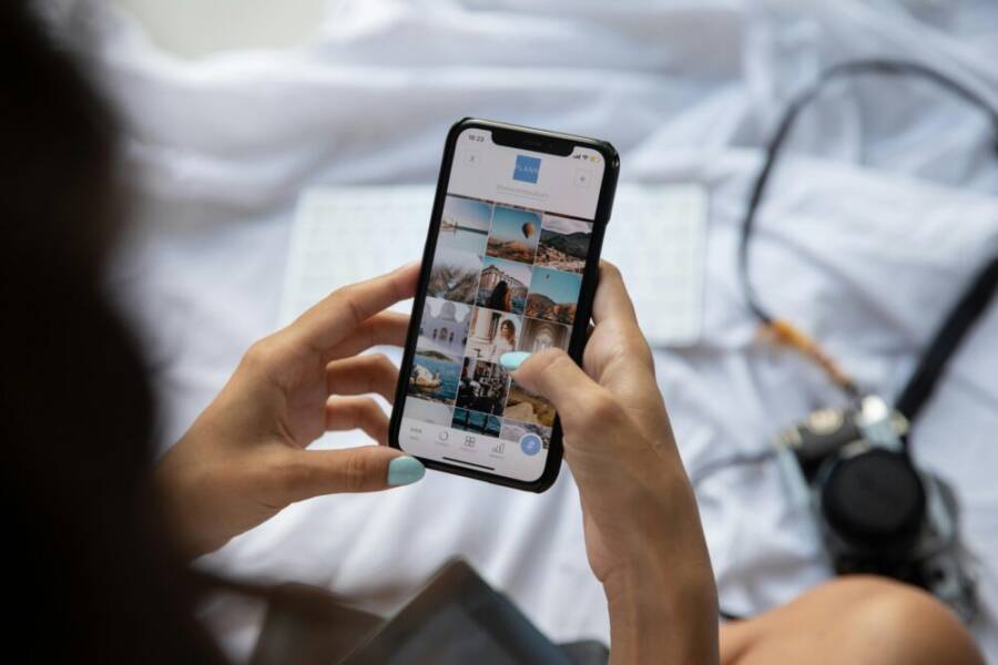 image: A person interacts with a smartphone displaying social media content in Bali, Indonesia.