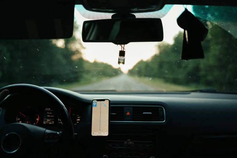 View of a car interior with a GPS on a scenic road during daytime travel