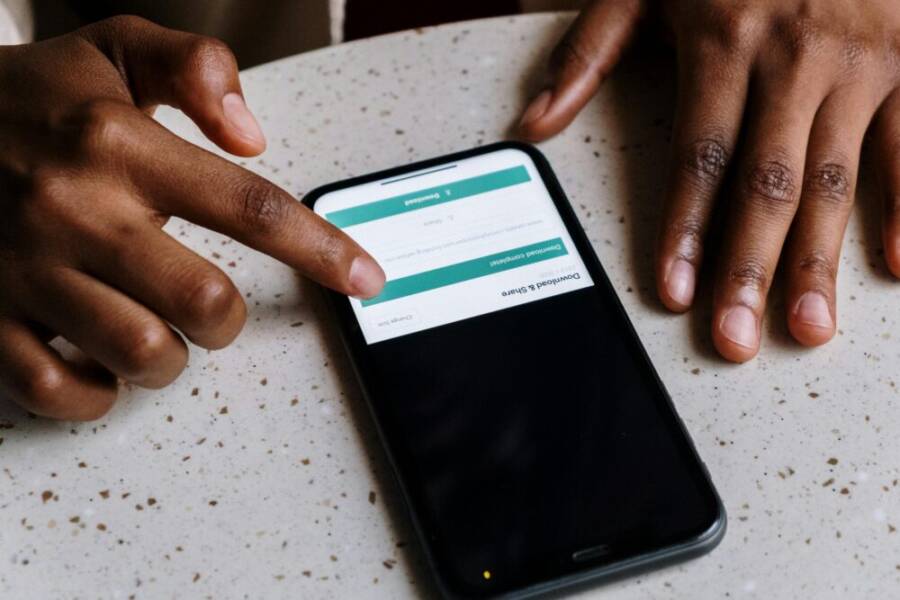 Close-up of hands interacting with a smartphone, displaying downloading interface