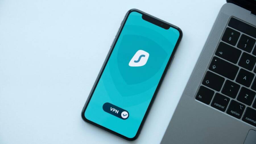 Flat lay of a smartphone showing a VPN app next to a laptop on a desk