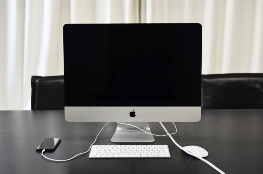 Modern convenient computer and mobile phone connected with wire on table in business office