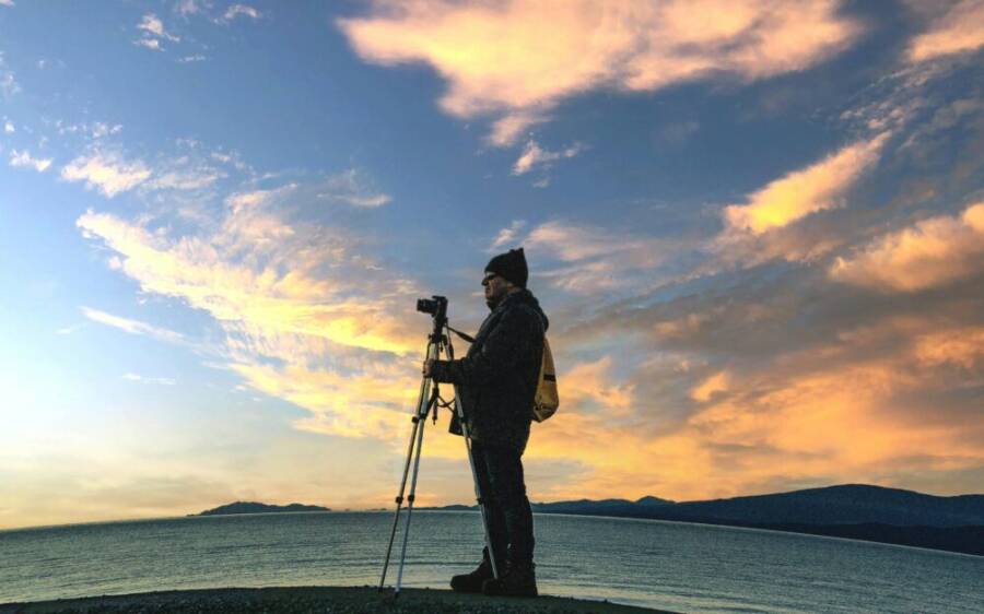 A photographer setting up a tripod on a beach