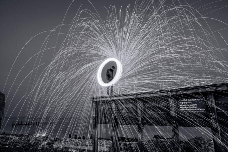 A captivating black and white long exposure photo of a fireworks display at night over a boardwalk