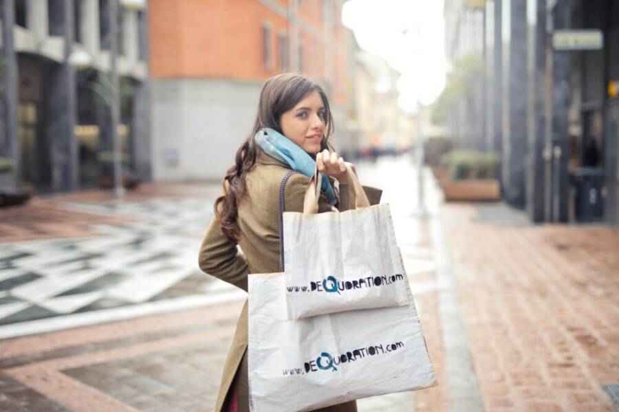 A fashionable woman shopping with bags in an urban street, exuding winter fashion style.