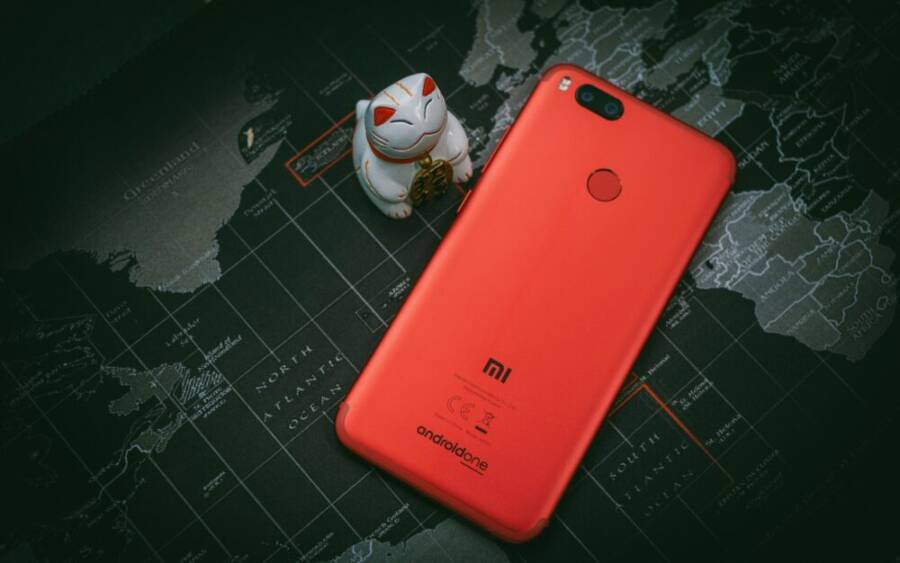 Red smartphone placed on a world map background with a cat figurine. Focus on modern technology.